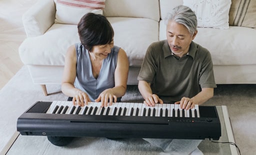 Wife and husband having a quality time together in they joint white appartment playing piano four hand
