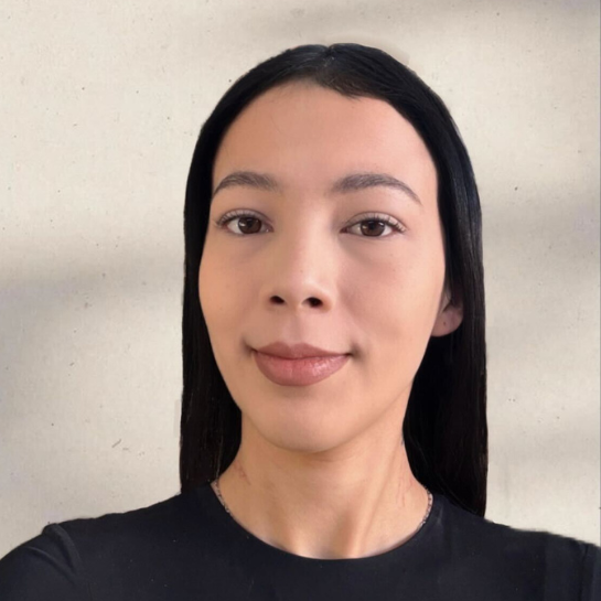vanessa Portrait of Vanessa Navarro, a young woman with sleek black hair, dressed in a black top, standing against a neutral background.
